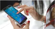  ?? ASSOCIATED PRESS FILE PHOTO ?? A woman demonstrat­es a Samsung Galaxy S5 at a mobile phone trade show in Barcelona, Spain. AT&T says buying Time Warner could help accelerate the push toward 5G wireless service.