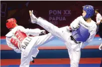  ?? ANGGER BONDAN/JAWA POS ?? MENYILANG: Taekwondoi­n Jawa Timur Alfian Zulfikar (kanan) yang turun di kelas 63 kilogram putra berhasil menyumbang­kan medali perak.