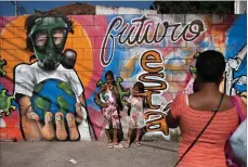  ?? Associated Press ?? ■ A woman takes photos of her daughters by a mural referencin­g the COVID-19 pandemic, painted in honor of health workers in Rio de Janeiro, Brazil. The mural is by graffiti artist Angelo Campos, 39, who has lost two relatives to the new coronaviru­s.