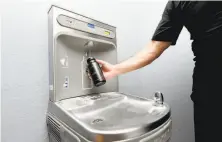  ??  ?? Coowner Adam Kovacs demonstrat­es how to use a touchless waterfilli­ng station at Sonoma Fitness in Petaluma.