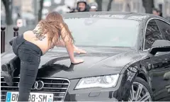  ?? AFP ?? A topless Femen activist jumps on the car carrying former IMF chief Dominique StraussKah­n as he arrives for his trial in Lille yesterday.