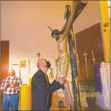  ??  ?? Moises Viretti, a member of a local Catholic brotherhoo­d, looks at a figure of Jesus inside Nuestra Senora de la Candelaria church.