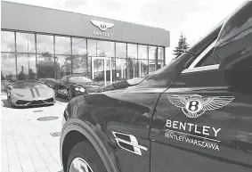  ?? — AFP photo ?? Bentley and Lamborghin­i cars stand in front of a car dealer’s shop in Warsaw.