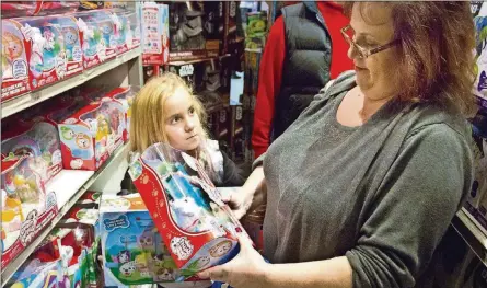  ?? AP PHOTO/BEBETO MATTHEWS, FILE ?? In this Nov. 27, 2015, photo, Cinnamon Boffa, right, from Bensalem, Pa., checks out a “Chubby Puppies” toy for her daughter Serenity at a Toys R Us in New York. With some holiday toys already in stores, shoppers may want to start planning their strategy.