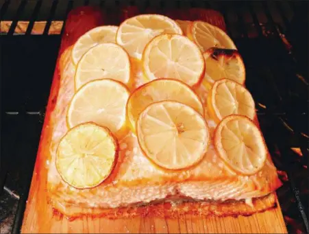  ?? ELIZABETH KARMEL VIA ASSOCIATED PRESS ?? This Wednesday, July 11, 2018 photo shows grilled salmon with lemon slices in Houston. This dish is from a recipe by Elizabeth Karmel.