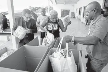  ?? SUSAN STOCKER/SOUTH FLORIDA SUN SENTINEL ?? Food for the Poor’s Angel Aloma and Marke Anderson, right, help Chris and Suzette Blair of Coral Springs as they drop off items for the agency’s Hurricane Dorian relief drive.