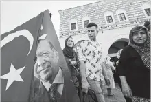  ?? LEFTERIS PITARAKIS THE ASSOCIATED PRESS ?? As Turkey's finance chief tried to reassure internatio­nal investors during a conference call Thursday, shoppers pass by a vendor selling flags.