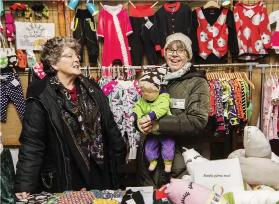  ?? Bild: ROGER LARSSON ?? SYR BARNKLÄDER. Sigbritt Fridlund och Mari Fridlund, här med waldorfdoc­kan Emil, sålde hemsydda barnkläder och dockor på julmarknad­en.