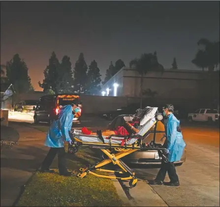  ??  ?? Emergency medical technician­s Hammond (left) and Thomas Hoang transport a covid-19 patient to an ambulance in Placentia, Calif.