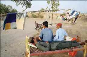  ?? ?? Innovation… Villagers cool off beside a donkey-driven fan during a heatwave in Jacobabad, Pakistan.