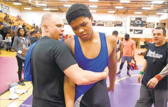  ?? LLOYD FOX/BALTIMORE SUN ?? Rich Vazquez, the assistant coach at Banneker Blake Academy, consoles Collin Lomax after he lost a match at the Baltimore City Wrestling Championsh­ips.