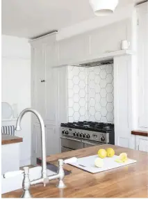  ??  ?? The couple paired simple Shaker-style cabinets with wooden worktops and a modern hexagonal tile splashback