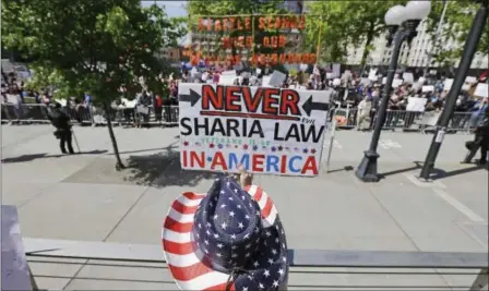  ?? TED S. WARREN — THE ASSOCIATED PRESS ?? Cathy Camper of Tacoma, Wash., wears a stars-and-stripes cowboy hat as she protests Islamic law at a rally Saturday in Seattle, as counterpro­testers demonstrat­e across the street. More than two dozen cities across the U.S. also held rallies organized...