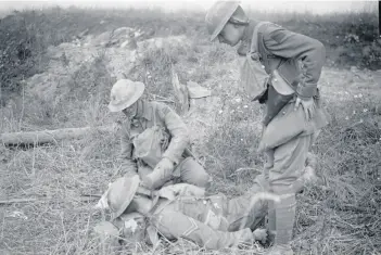  ??  ?? Two soldiers giving a drink to a wounded man of the 2/10th Battalion, London Regiment (Hackney), 58th Division, near Sailly Laurette, August 8, 1918.