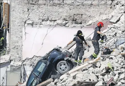  ?? AP PHOTO ?? Rescuers make their way through destroyed houses following Wednesday’s earthquake in Pescara Del Tronto, Italy, Thursday.