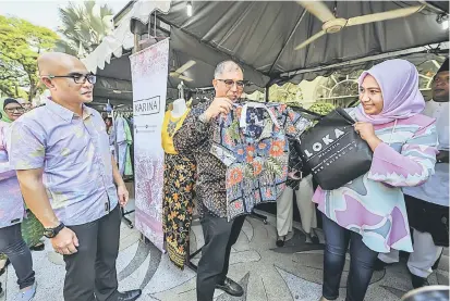  ?? — Gambar Bernama ?? TARIKAN: Muhammad Bakhtiar (tengah) beramah mesra dengan Pengasas LOKA Malaysia Juliahayyu Mohamad (kanan) ketika melawat gerai jualan pakaian batik selepas Pelancaran Batik Fest 2019 di Pusat Pelanconga­n Malaysia (MaTiC), semalam.