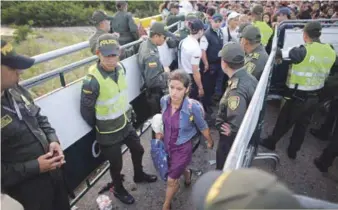  ?? AP ?? Crisis. En esta foto de archivo del 17 de julio de 2016, la policía monta guardia mientras una mujer venezolana cruza a Colombia a través del puente Simón Bolívar que une a San Antonio del Táchira, Venezuela.