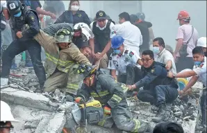  ?? YURI CORTEZ / AFP ?? Rescuers hold a firefighte­r as he cuts away debris from a flattened building during a search for survivors on Tuesday after a powerful earthquake hit south-central Mexico.