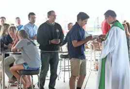  ?? MICHAEL SEARS / MILWAUKEE JOURNAL SENTINEL ?? People receive Holy Communion from the Rev. Tim Kitzke at Major Goolsby’s Summerfest Mass on Sunday. To view a photo gallery, go to jsonline.com/news.