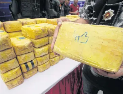  ?? PORNPROM SATRABHAYA ?? A police officer yesterday shows a package containing 10,000 methamphet­amine pills at a press conference. The package was among dozens seized containing about 1.9 million speed pills from a townhouse in tambon Sam Ruen in Ayutthaya’s Bang Pa-in district.