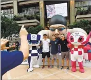  ?? Kazuhiro Nogi AFP/Getty Images ?? PEOPLE take photos with 2020 Olympic mascots Miraitowa, left, and Someity on Tuesday in Tokyo.