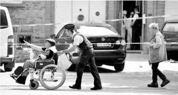  ?? — Reuters photo ?? A Belgian policeman pushes a man on a wheelchair as his colleagues get out of a house after searching it, following yesterday’s attack, in Brussels, Belgium.