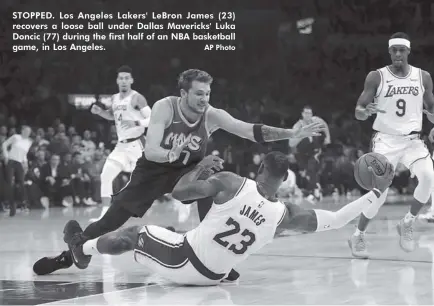  ?? AP Photo ?? STOPPED. Los Angeles Lakers' LeBron James (23) recovers a loose ball under Dallas Mavericks' Luka Doncic (77) during the first half of an NBA basketball game, in Los Angeles.