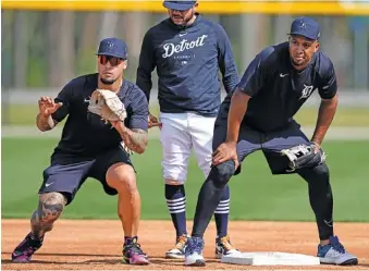  ?? AP PHOTO/DAVID J. PHILLIP ?? Detroit Tigers infielders Javier Baez, left, and Jonathan Schoop, right, work on drills at second base during Sunday’s spring training workout in Lakeland, Fla.