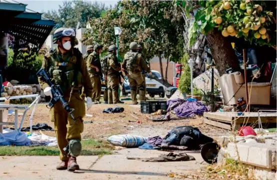  ?? THOMAS COEX/AFP/GETTY IMAGES ?? Israeli soldiers stood near a Palestinia­n militant’s body in Kfar Aza, in the south of Israel, bordering Gaza Strip on Oct. 10.