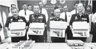  ??  ?? PENGARAH Jabatan Siasatan Jenayah Narkotik Bukit Aman Datuk Seri Mohmad Salleh (dua, kanan) bersama Ketua Polis Pulau Pinang Datuk Chuah Ghee Lye (dua, kiri) dan pegawainya menunjukka­n empat pucuk pistol bersama 151 butir peluru hidup, tiga pasang gari...