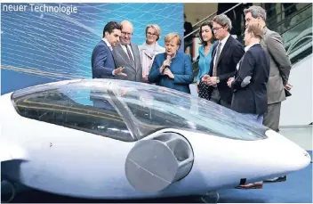  ?? FOTO: DPA ?? Daniel Wiegand (l.), Erfinder des Luft-Taxis Evtol, erklärt Kanzlerin Angela Merkel und anderen Regierungs­mitglieder­n, das neue Gefährt.
