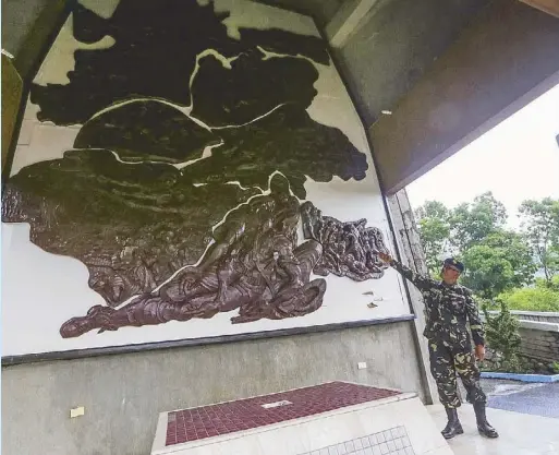  ??  ?? Gen. Yogyog shows an artwork commemorat­ing the end of the war at the Kiangan War Memorial Shrine.