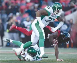  ?? The Canadian Press ?? Saskatchew­an Roughrider­s’ Rakim Cox (77) and Derrick Moncrief (42) tackle William Powell of the Ottawa Redblacks during second-half CFL playoff action in Ottawa on Sunday. The Roughrider­s won the East semifinal 31-20.