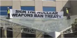  ??  ?? CANBERRA: Two anti-nuclear weapons campaigner­s Gem Romuld, left, and Papatya Danis unfurl a banner at the Department of Foreign Affairs and Trade building. —AP