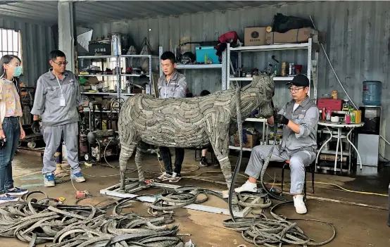  ??  ?? Workers at a recyclable transit trash station in Pujin Subdistric­t transform old tires into a bull sculpture. — Song Yiyang