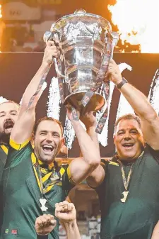  ??  ?? Australian captain Cameron Smith and coach Mal Meninga hold aloft the Rugby League World Cup at Suncorp Stadium last night