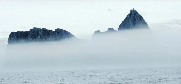 ?? DAPHNE BRAMHAM ?? The peaks of Elephant Island poke through the fog, providing a glimpse of the inhospitab­le conditions that greeted Ernest Shackleton’s expedition crew in the early 1900s.