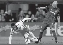  ?? The Associated Press ?? Columbus Crew’s Ola Kamara, left, falls while trying to kick the ball away from Toronto FC’s Michael Bradley Nov. 21 in Columbus.