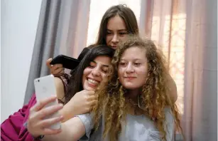  ?? (Raneen Sawafta/Reuters) ?? PALESTINIA­N TEENAGER Ahed Tamimi, who was released from Israeli prison on Sunday, takes a selfie with friends at her family’s house in Nabi Saleh on Monday.