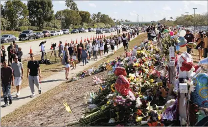  ?? PICTURE: AP ?? Parents and students walk next to the memorial for the victims of the shooting at Marjory Stoneman Douglas High School. It was an open house on Sunday as parents and students returned to the school for the first time since 17 victims were killed in a...