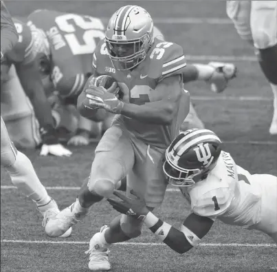  ?? JAMIE SABAU/GETTY ?? Ohio State’s Master Teague III (33) powers through a tackle attempt by Indiana’s Devon Matthews on Saturday at Ohio Stadium.