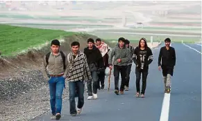  ??  ?? On the open road: A group of Afghan migrants walking along a main road after crossing the Turkey-Iran border near Dogubayazi­t, Agri province, eastern Turkey.