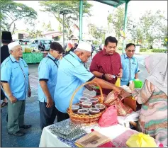  ??  ?? Lukanisman (facing camera, second right) and Ali on his right make a stop at one of the stalls during the charity sale at Piasau Jaya Phase 2 futsal court.