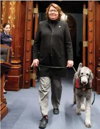  ?? JACQUES BOISSINOT/THE CANADIAN PRESS ?? Coalition Avenir Québec MNA Claire Samson walks in the legislatur­e with her assistance dog, Pepper. The dog, who helped Samson by warning her when an epileptic seizure was imminent, has died. Samson says her illness has worsened.