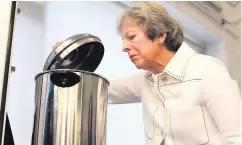  ??  ?? Prime Minister Theresa May peers into a hot water urn as she helps make drinks during a visit to social group in Vauxhall, south London, yesterday