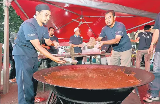  ?? — Gambar Bernama ?? BERTUKAR WARNA: Sukarelawa­n membungkus bubur Asyura yang telah siap dimasak untuk diagihkan pada masyarakat setempat pada program gotong-royong memasak Bubur Asyura Pantai Timur anjuran Kelab Media Massa Melaka (KEMM) bersama Persatuan Kebajikan...