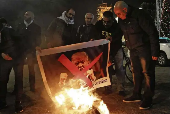  ?? Musa al Shaer/AFP ?? Palestinos queimam foto de Donald Trump em Belém (Cisjordâni­a) para protestar contra mudança da Embaixada dos EUA em Israel para Jerusalém