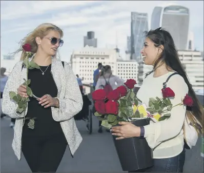  ?? PICTURES: PA. ?? FLOWER POWER: Roses with messages are given out to passers-by on London Bridge just over a week on from the terror attack.