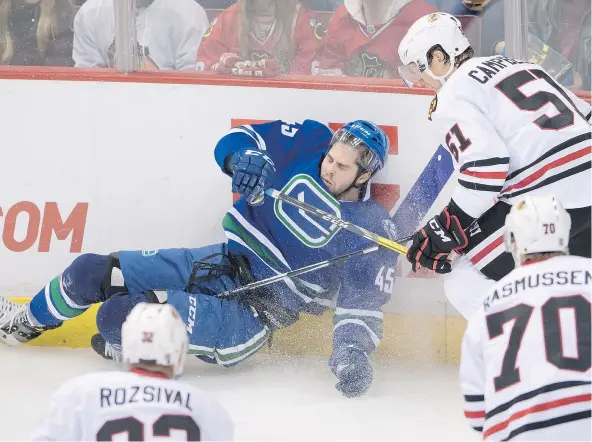  ?? — THE CANADIAN PRESS FILES ?? Vancouver Canucks’ Michael Chaput crashes into the boards in front of Chicago Blackhawks’ Brian Campbell, top right, during Saturday’s game in Vancouver. The Canucks allowed the Blackhawks to come back and win the game in overtime