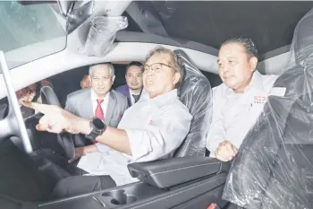  ?? — Photo by Chimon Upon ?? Abang Johari sits in the driver’s seat to get a feel inside the Tesla Model Y. Behind him is Abdul Aziz, while on his right is Ismail.